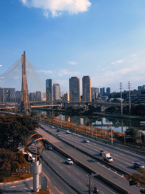 Free Aerial view of São Paulo showcasing the iconic Estaiada Bridge and busy highways under a blue sky. Stock Photo