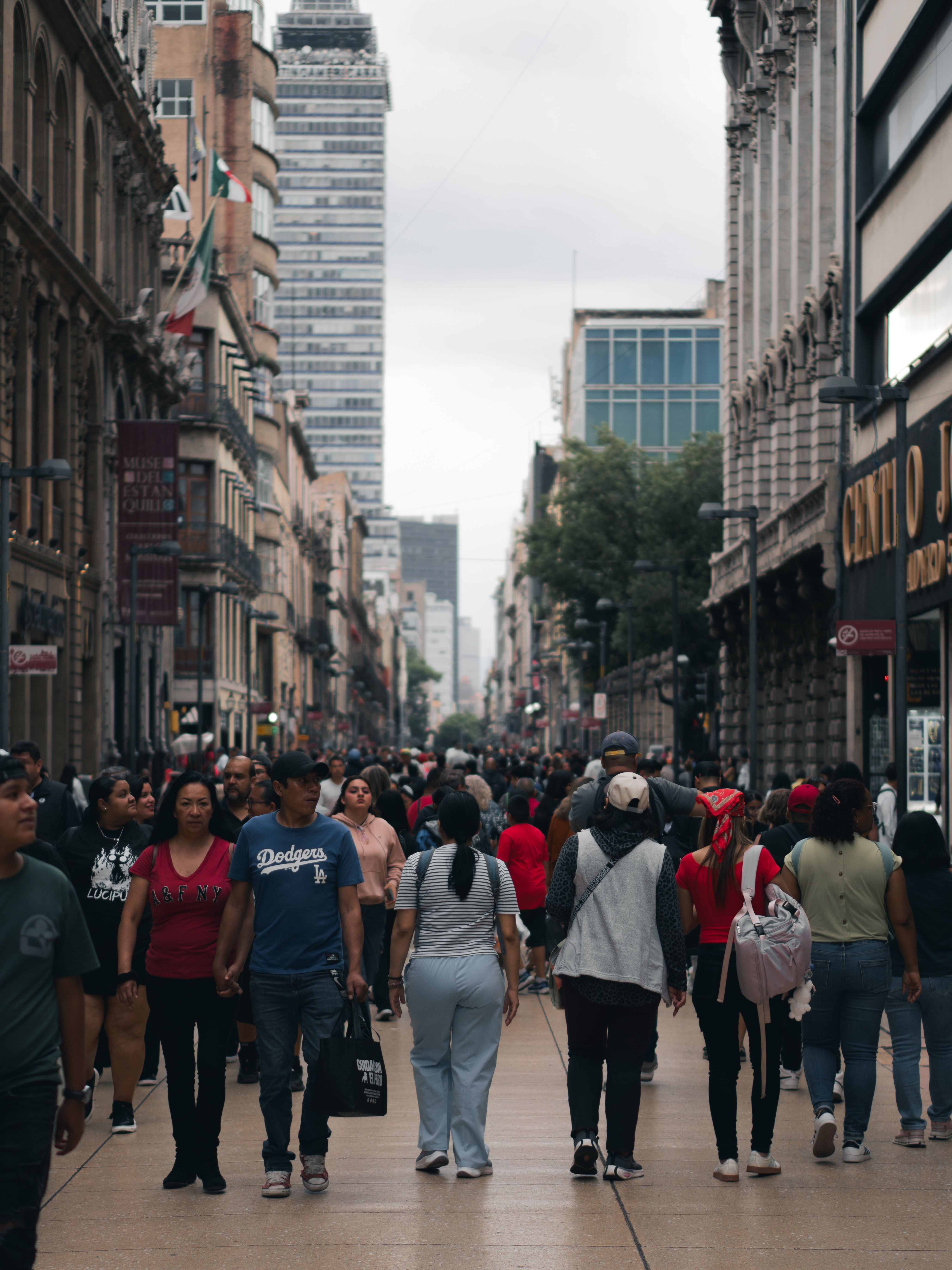 A vibrant and crowded street scene in Mexico City with diverse pedestrians and towering buildings.
