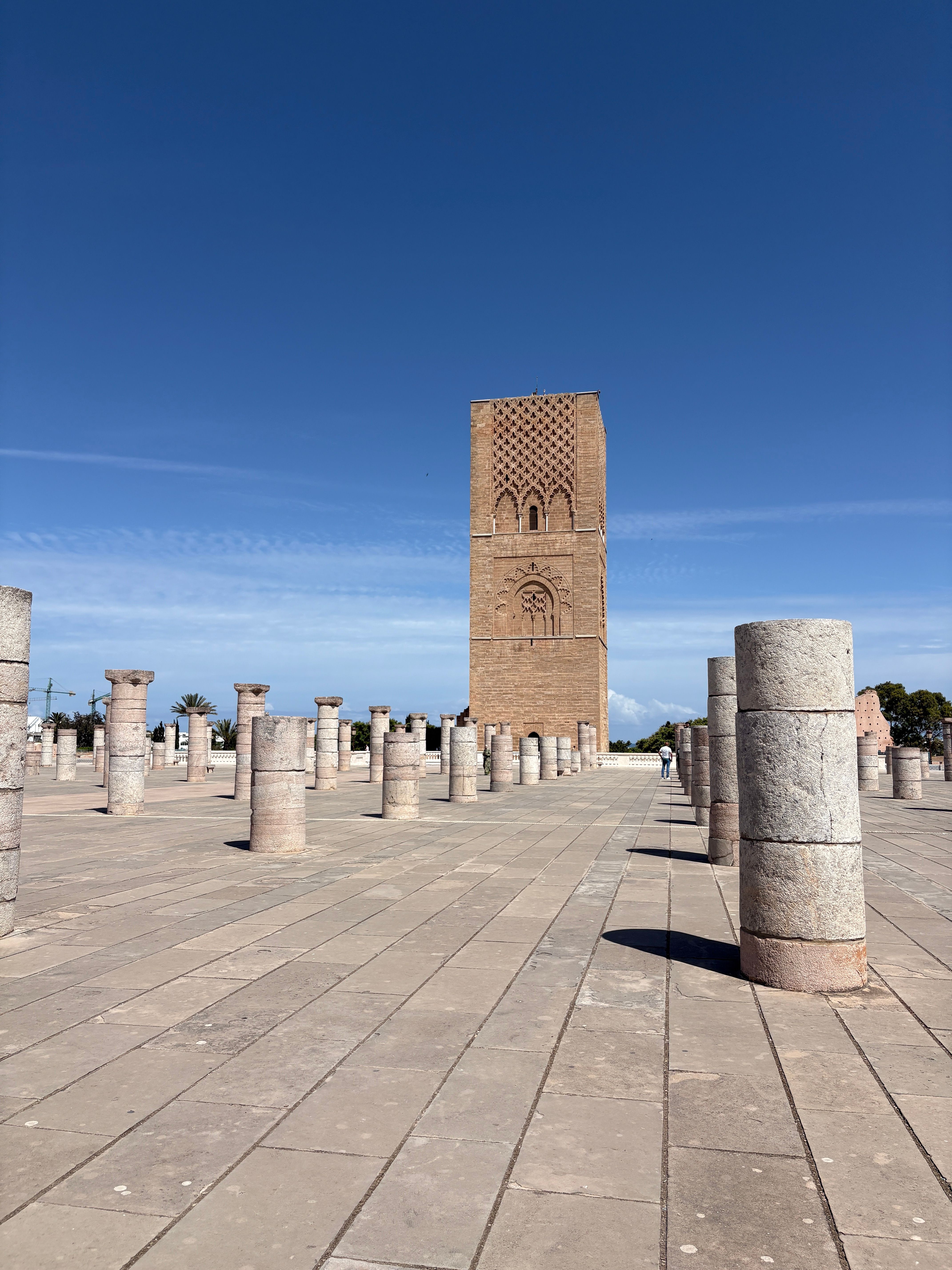 View of the historic Hassan Tower and columns in Rabat, Morocco, with a clear blue sky.