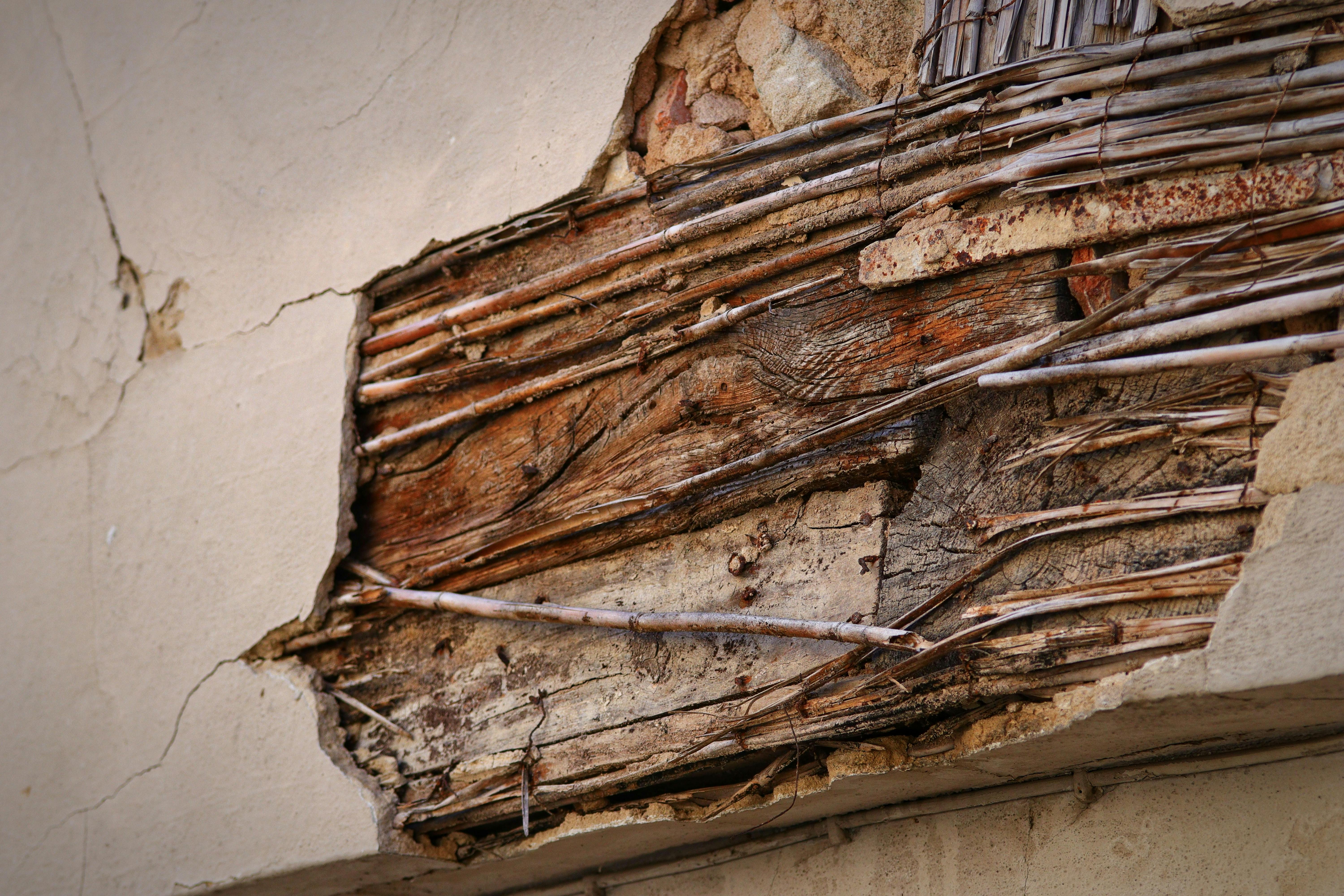 Detailed view of an old wall showing exposed wooden structure and cracks.
