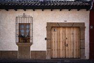 Charming adobe house facade with traditional architecture in Antigua Guatemala features a wooden door and barred window.