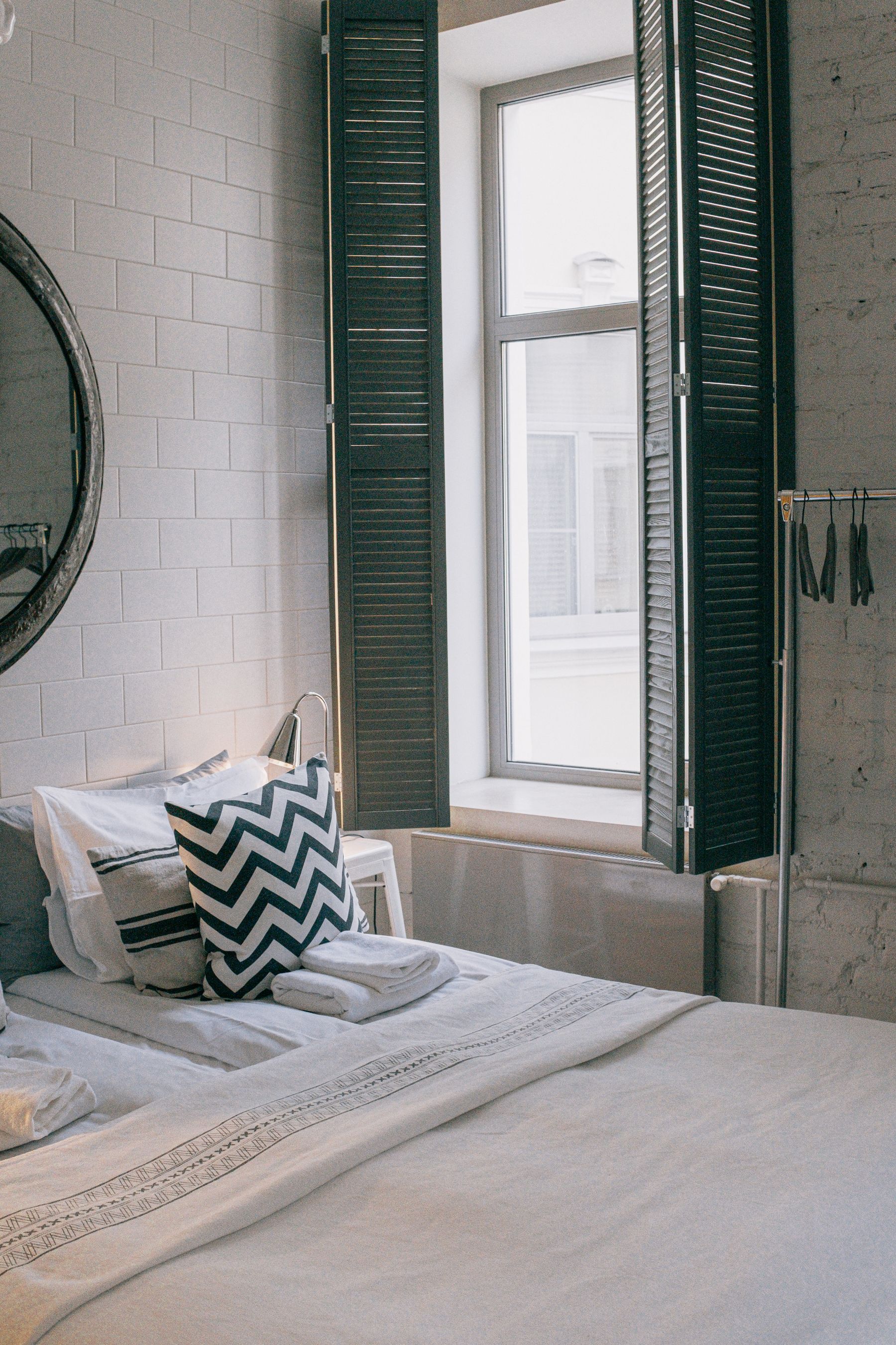 White bed with a blue and white striped cushion in soft daylight