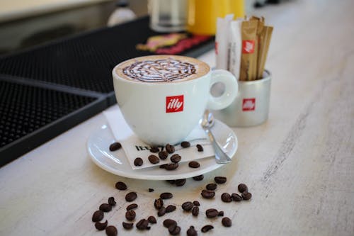 White Ceramic Mug on Saucer With Coffeebeans