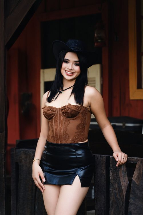 Free Smiling woman in Western-style outfit outdoors, exuding confidence and style. Stock Photo
