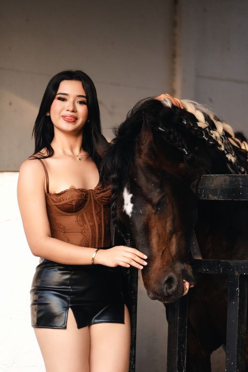 Free Woman posing with a horse inside a stable, highlighting bond and elegance. Stock Photo