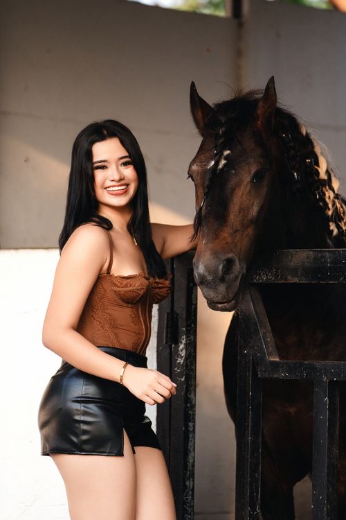 Free Smiling young adult woman with a horse in an indoor stable. Calm and joyful atmosphere. Stock Photo