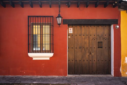 Free Vibrant colonial architecture with a wooden door and barred window in Antigua Guatemala. Stock Photo