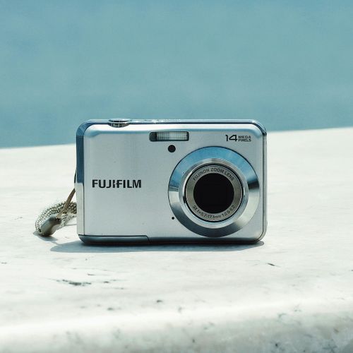 Free Close-up of a silver digital camera on a marble surface against a blue sky background. Stock Photo