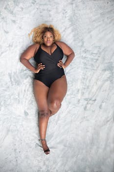 一名大码女子自信地穿着黑色泳衣，在纹理表面上摆出姿势