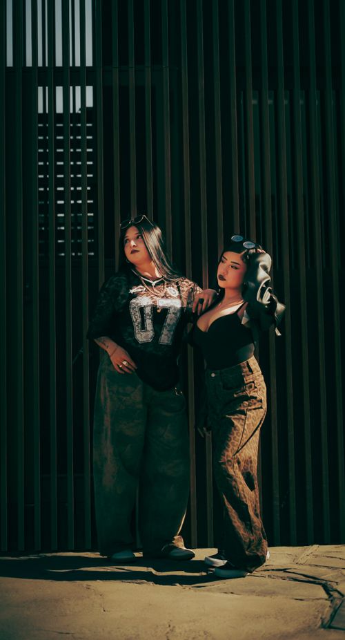 Free Stylish women pose in front of a slatted wall, showcasing urban fashion. Stock Photo
