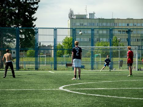 Teenagers enjoying a soccer game on an outdoor field in Wrocław, Poland.