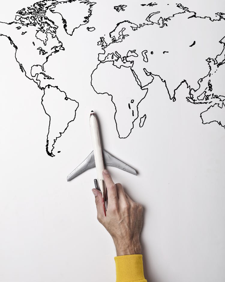 Person Holding Small Toy Airplane Against Black And White Map As Concept Of Travel And Vacation