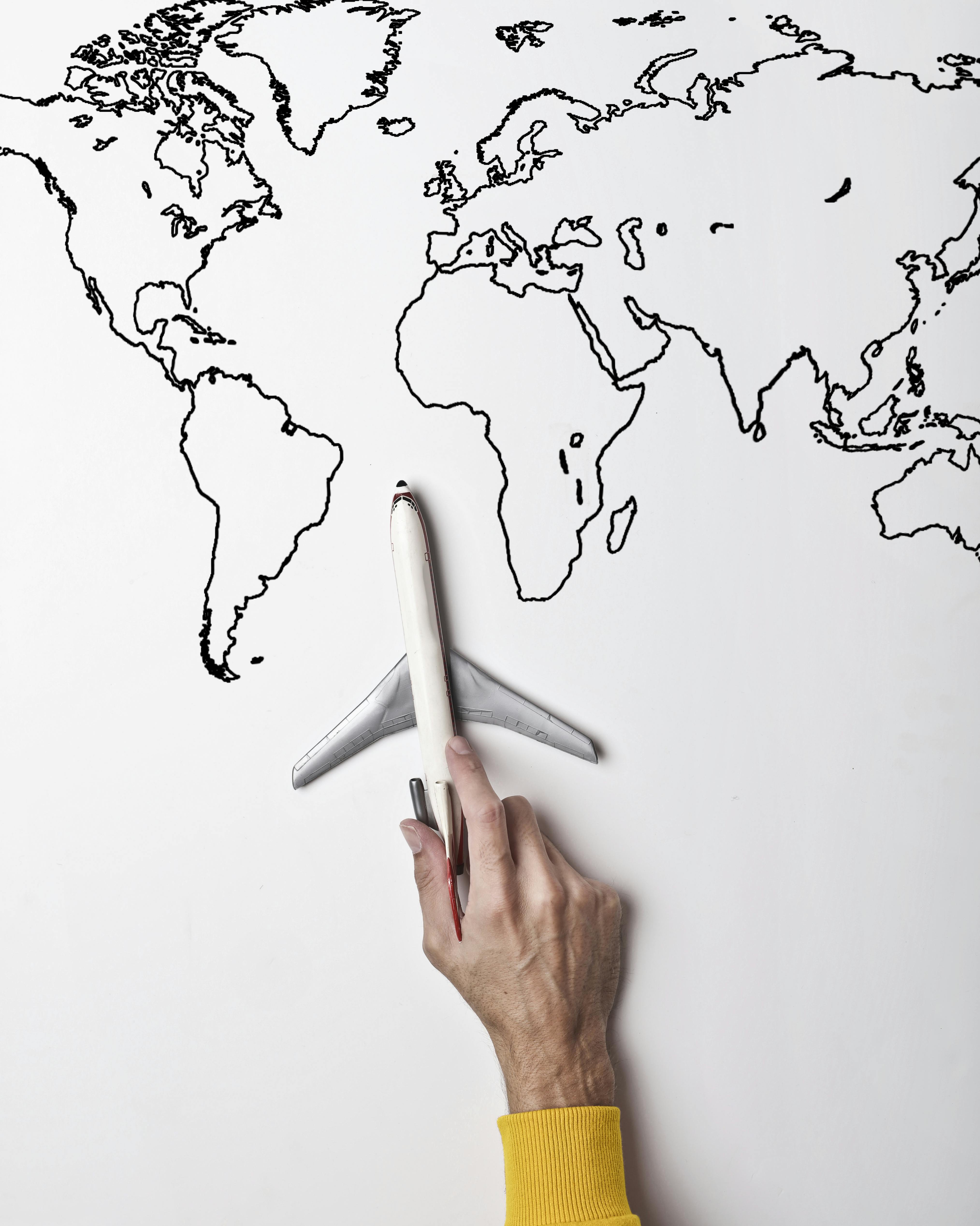 Person holding small toy airplane against black and white map as concept of travel and vacation ...