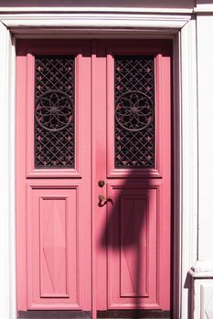 Ornamental pink wooden door with intricate ironwork, located in Jönköping, Sweden.