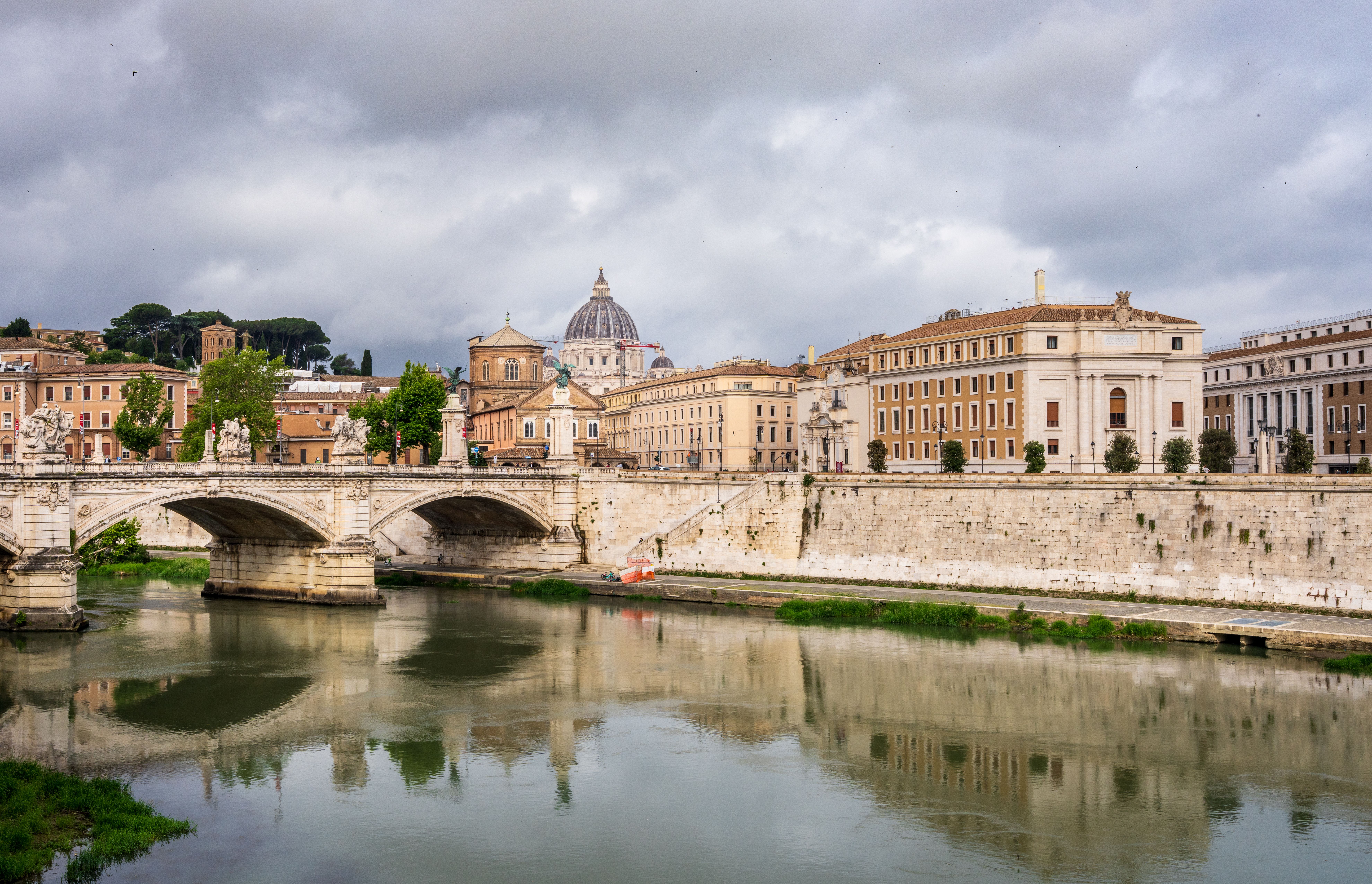 View of Ponte Sant'Angelo over the Tiber River with Saint Peter's Basilica in the background.