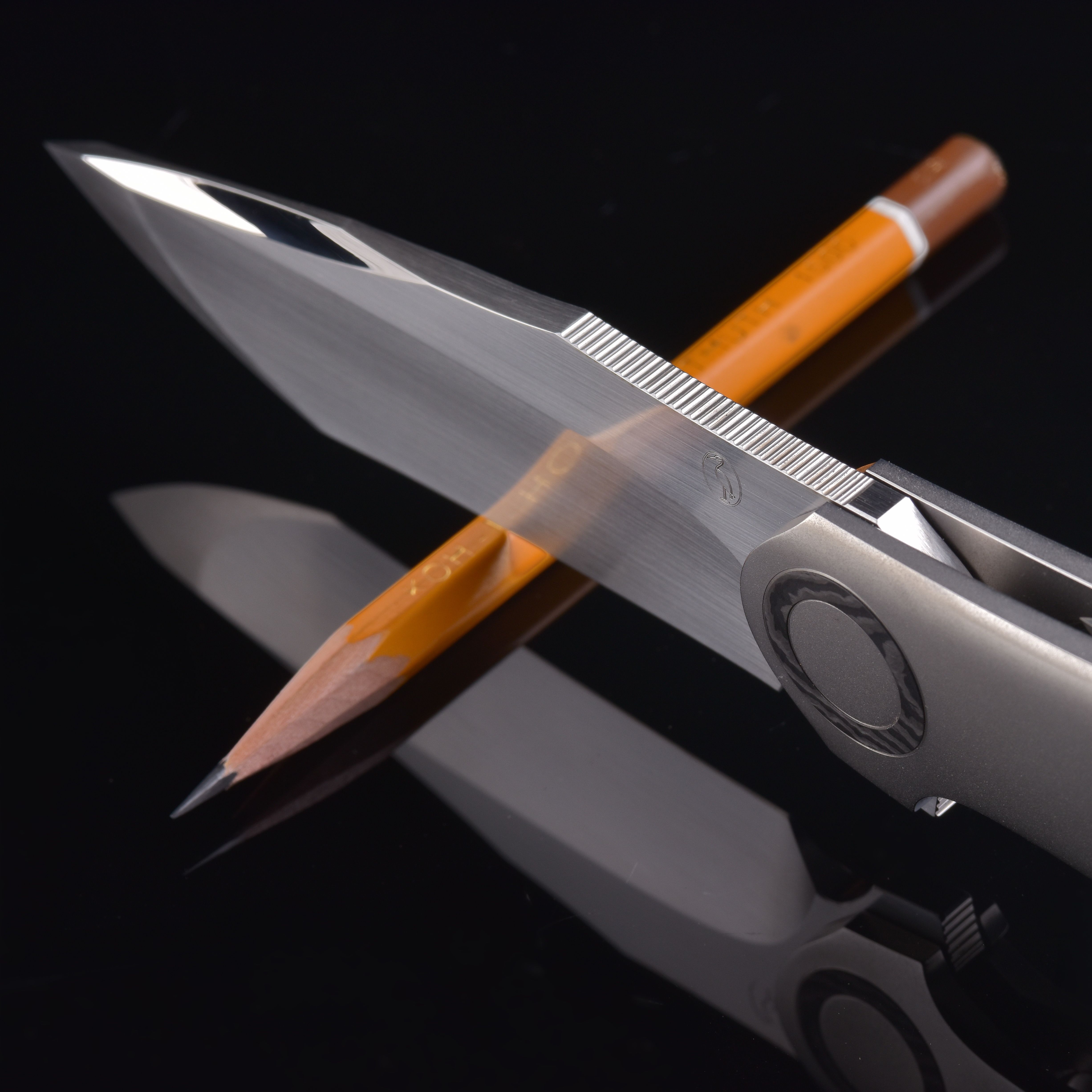 A sharp knife precisely balanced on a pencil with a clear reflection on a glossy black surface.