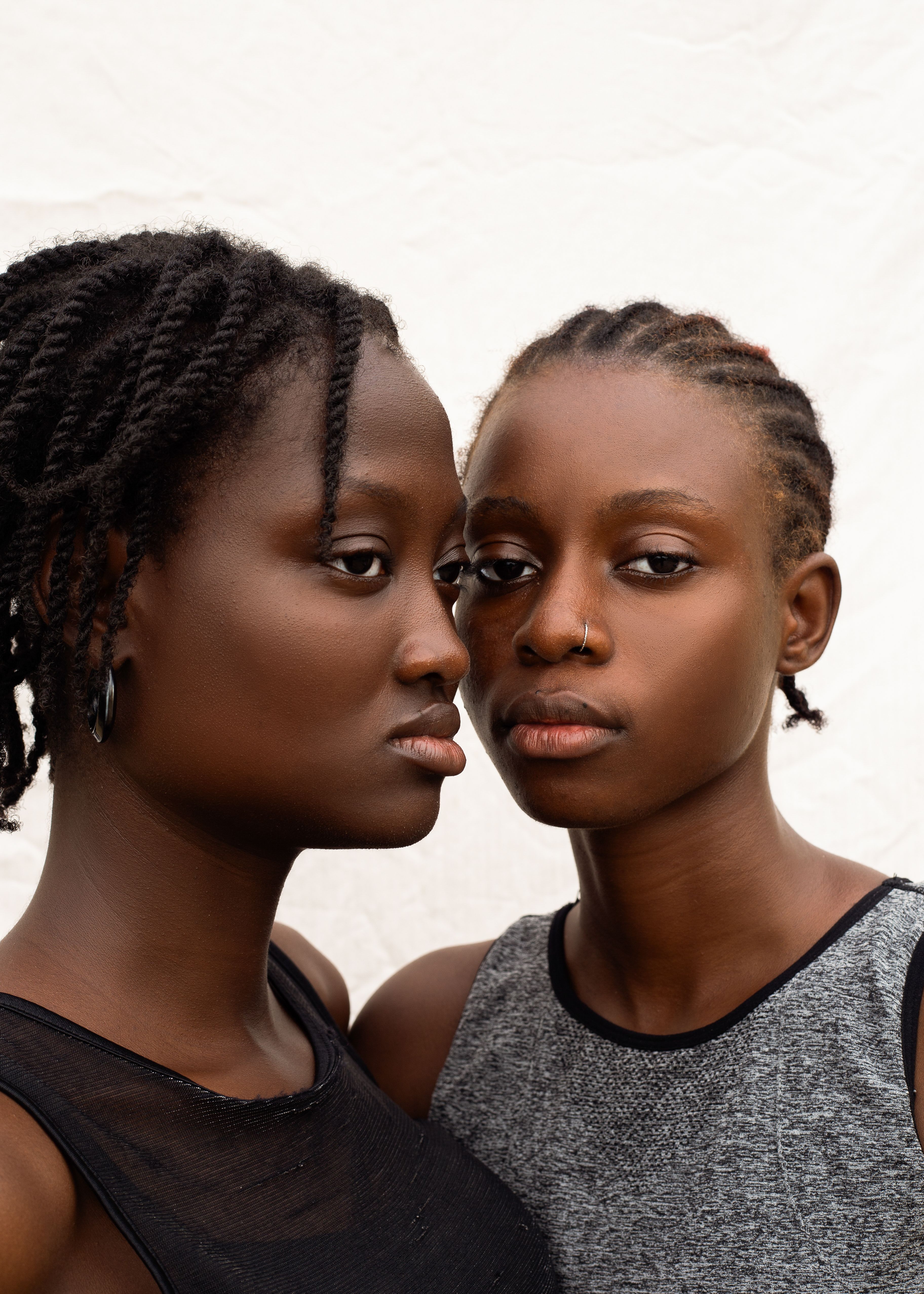 Intimate portrait of two women in casual outfits with braided hairstyles.