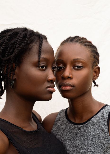 Intimate portrait of two women in casual outfits with braided hairstyles.