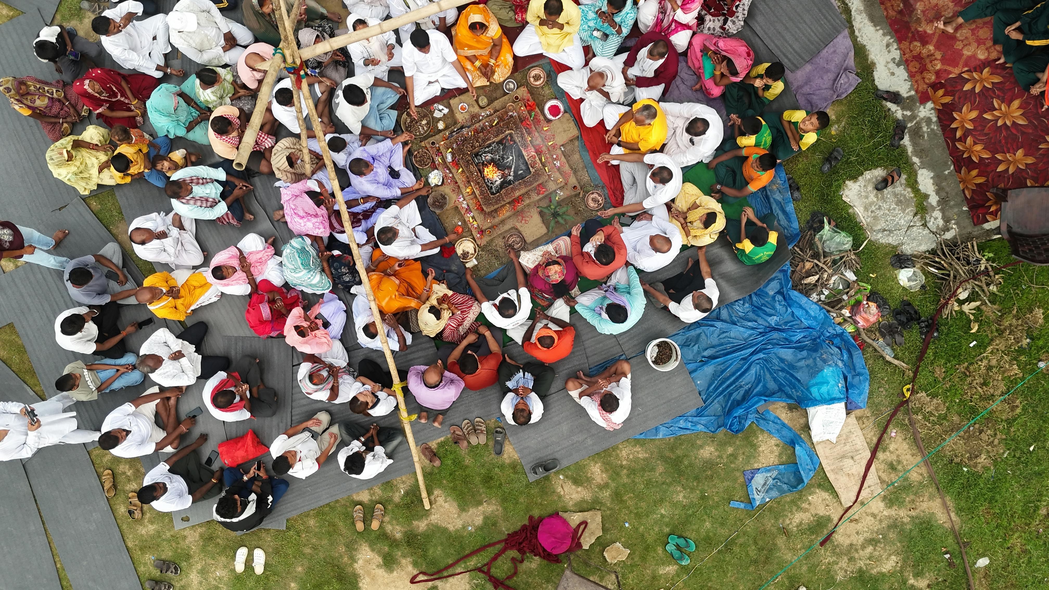 A diverse group of people sitting in a circle, hands joined in prayer or meditation