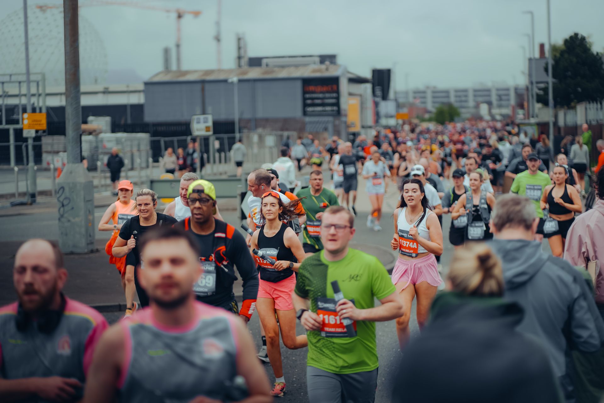 A dense field of road runners in race bibs filling a city street during a mass-participation marathon