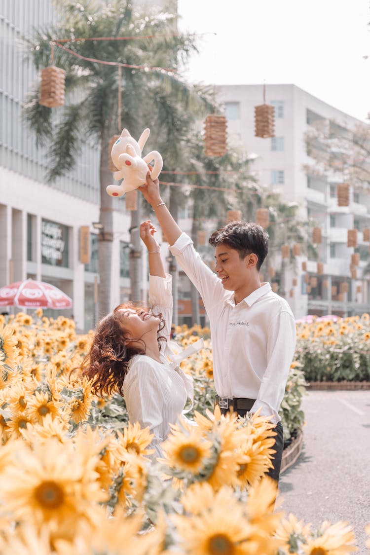 Happy Ethnic Couple Having Fun Near Blooming Sunflowers In Sunlight