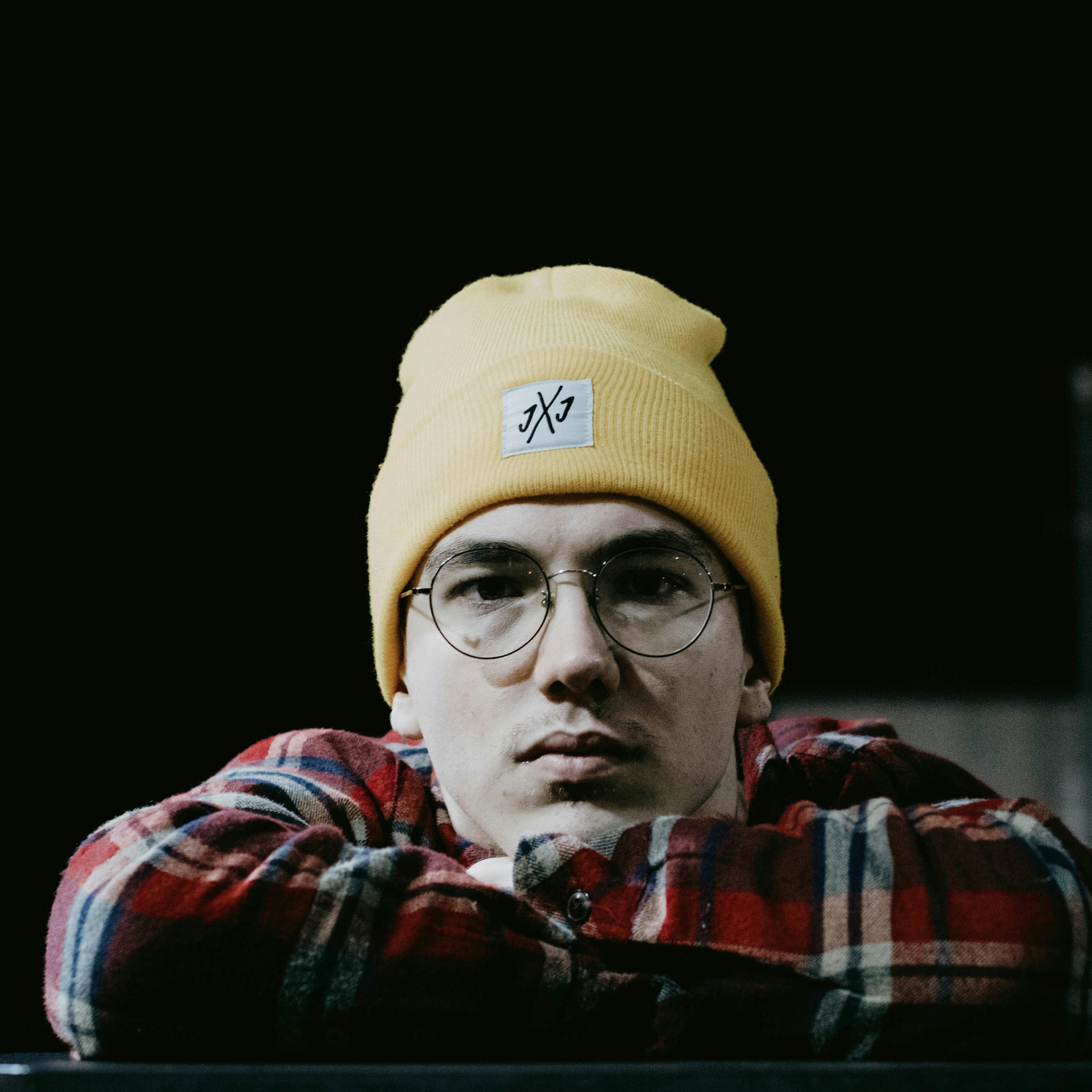 Actor on a red carpet wearing a sharp black outfit with photographers in the background