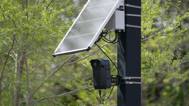 solar panel mounted on a camera bracket under an eave of a suburban house