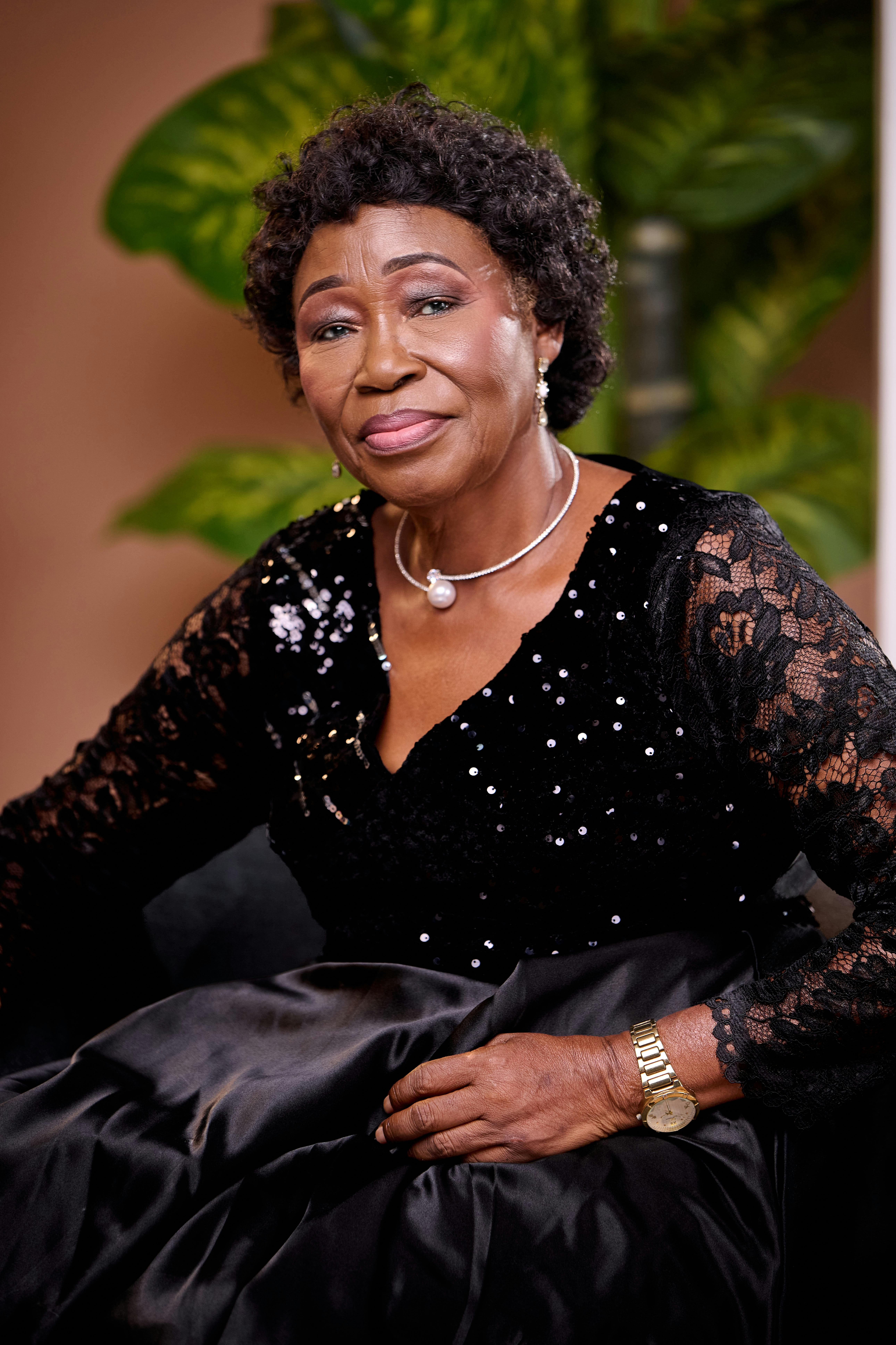 Sophisticated portrait of a senior woman in an elegant black dress with pearl jewelry, exuding grace and style.