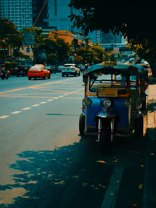 Free Colorful tuk-tuk on a bustling street in Bangkok, Thailand, with city life and traffic in the background. Stock Photo