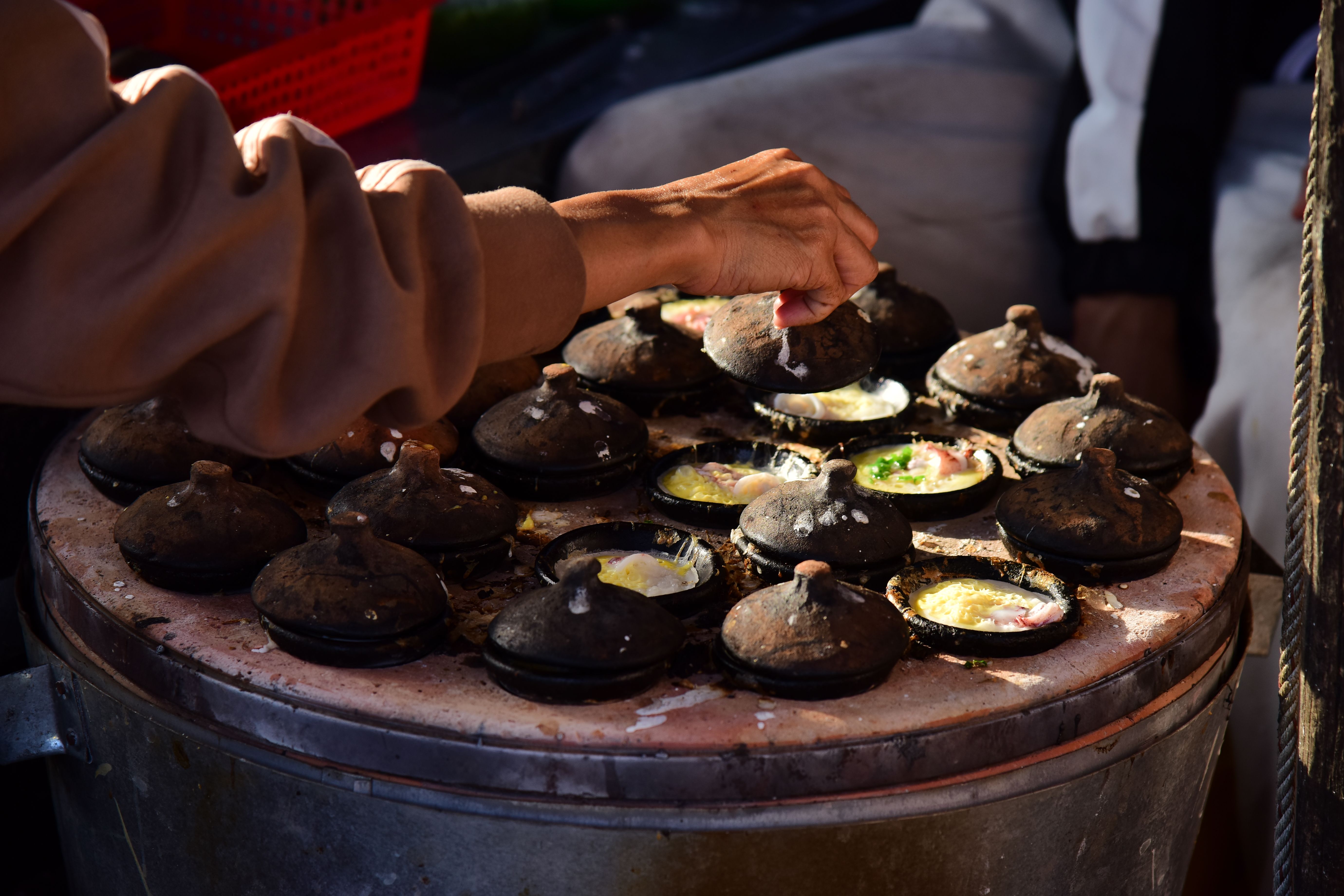 Hands grating coconut beside a clay pot of fish curry during a cooking class near Fort Kochi