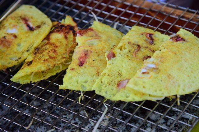 Crispy Vietnamese Bánh Xèo sizzling on a grill with fresh ingredients.