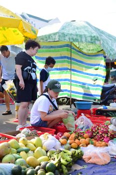 A bustling outdoor market with people shopping for fresh fruits and vegetables in Asia.