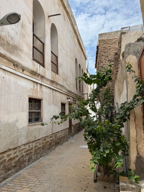 Free Charming narrow alley with rustic stone buildings and lush greenery under a bright sky. Stock Photo