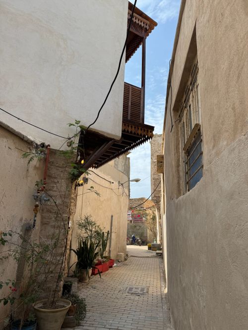 Free A narrow alleyway with plants in pots and traditional wooden architecture overhead on a sunny day. Stock Photo