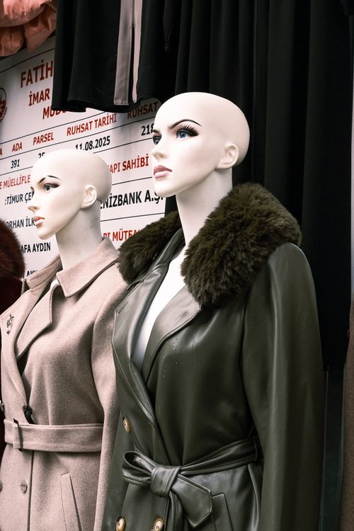 Free Mannequins showcasing elegant winter coats in an outdoor street market setting. Stock Photo