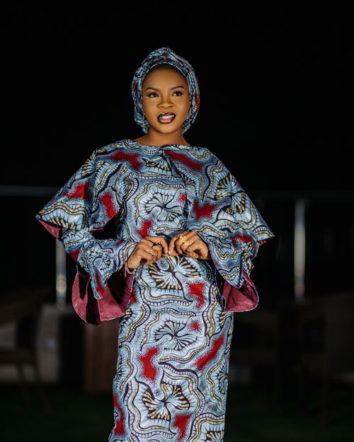 Free Smiling woman in vibrant traditional African clothing against a dark background. Stock Photo