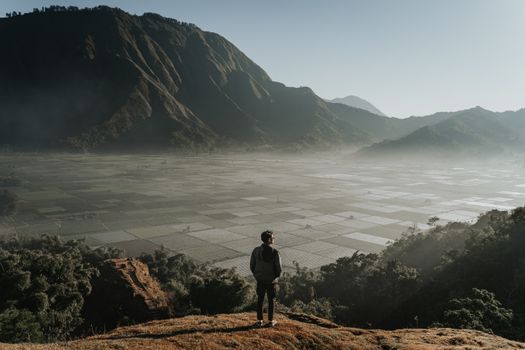 A traveler observes the sunrise over the expansive rice fields in West Nusa Tenggara, Indonesia.
