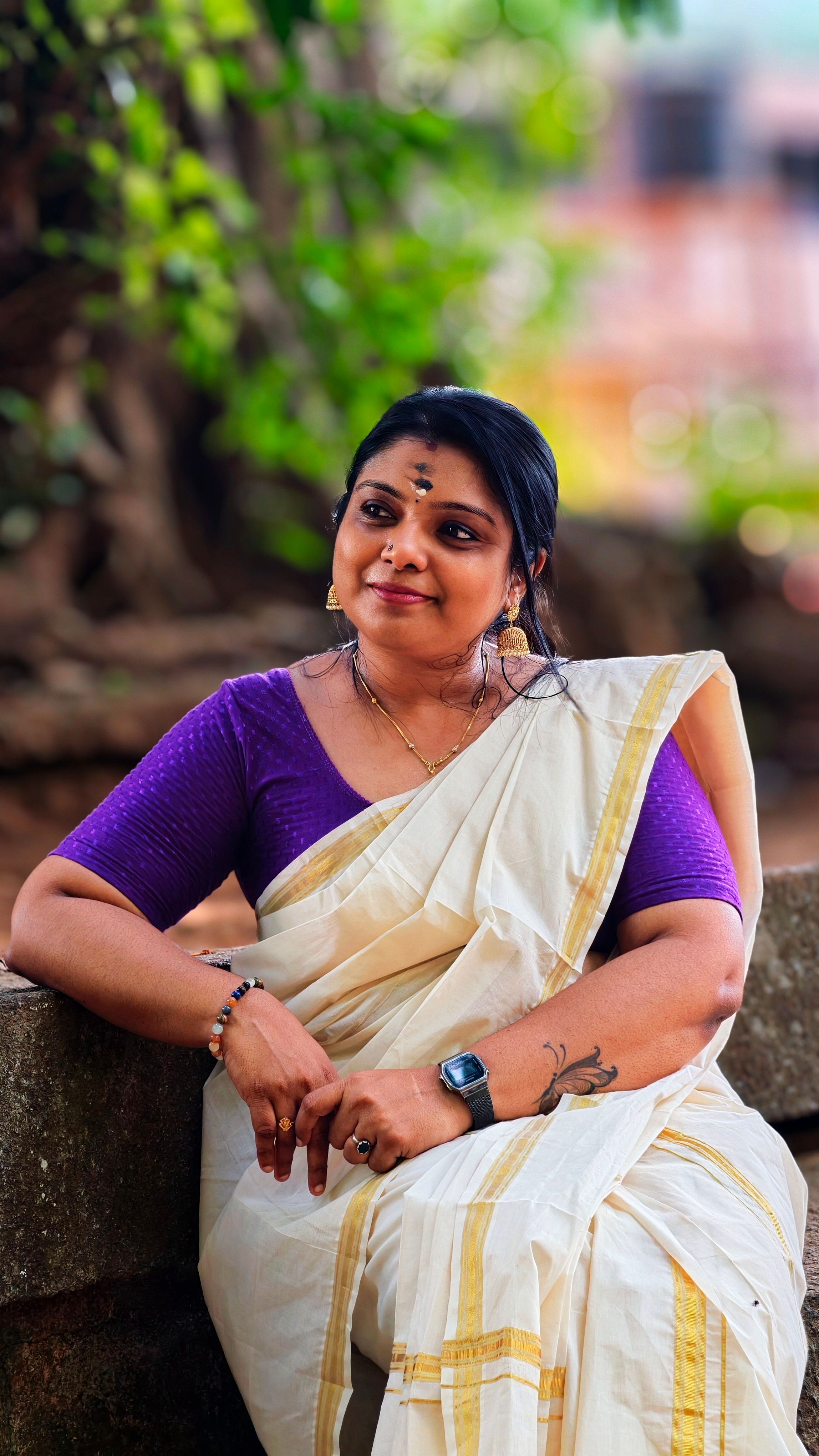 Elegant portrait of a woman in traditional Kerala Kasavu saree with cultural jewelry outdoors.