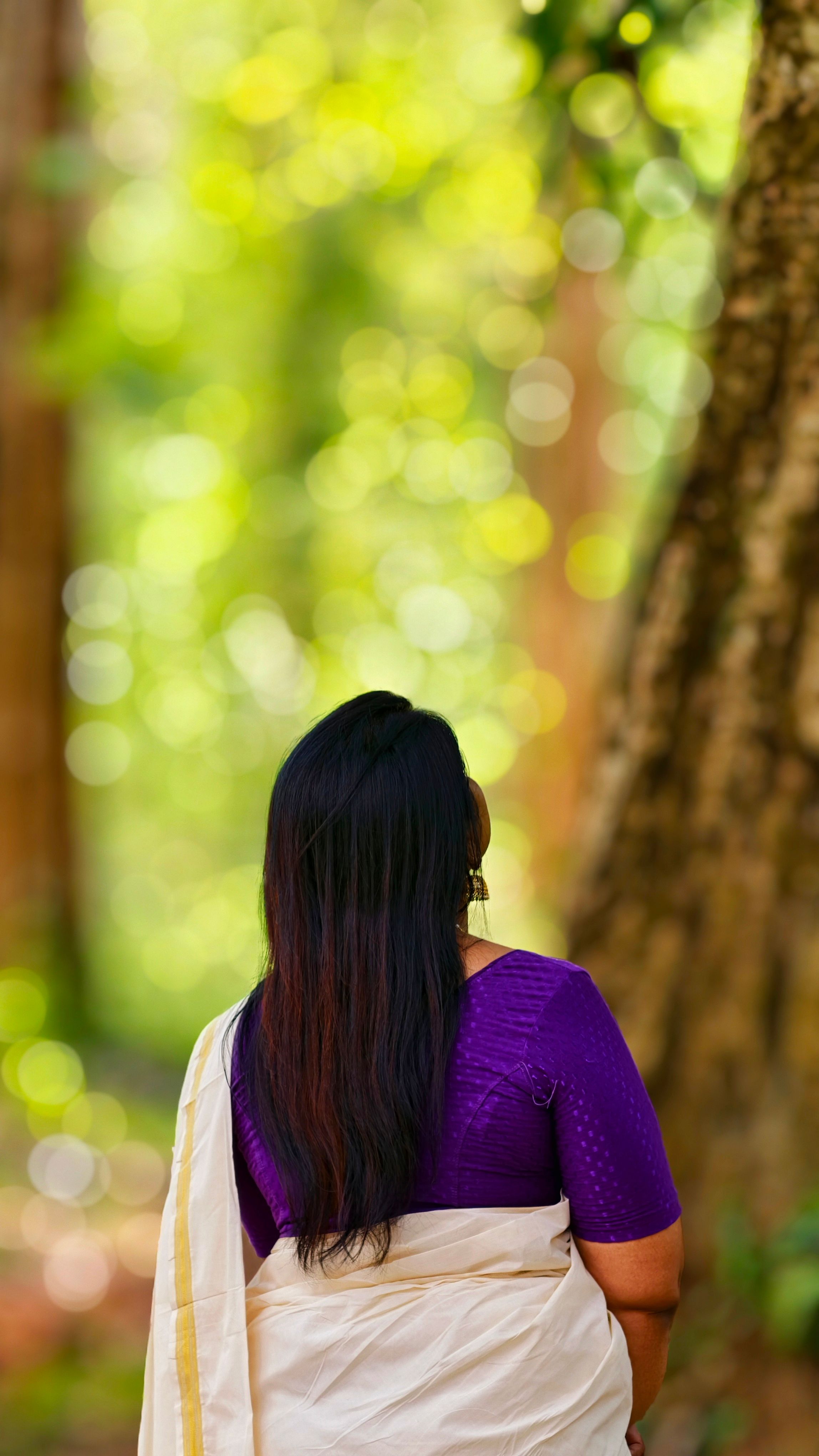 A woman in a traditional Kerala saree enjoys a serene moment in a lush forest.