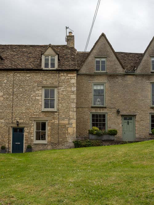 Free Quaint stone houses in Tetbury, England with lush green lawns on an overcast day. Stock Photo