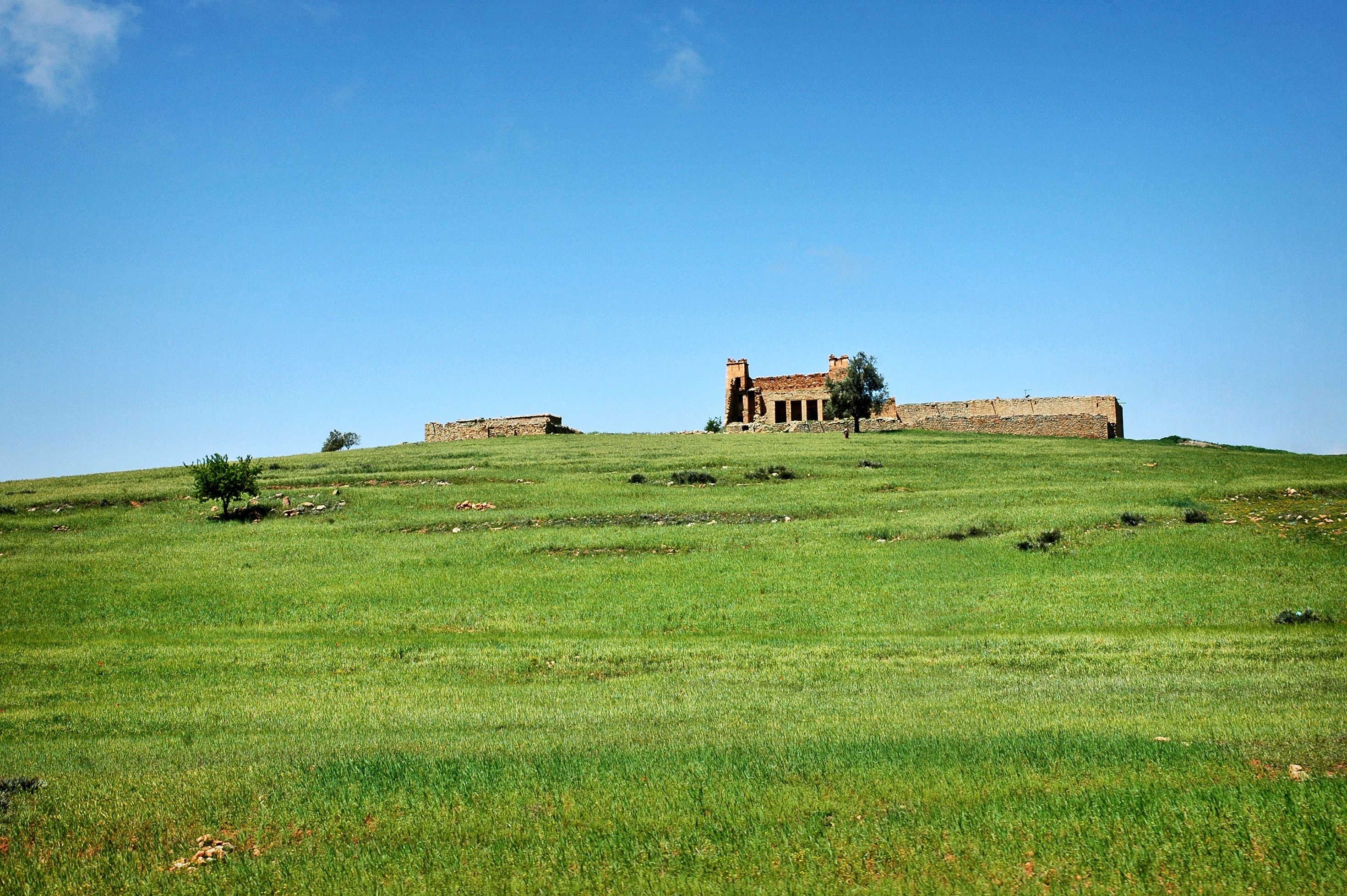 A picturesque view of historical ruins atop a green hill in Béni Mellal, Morocco.