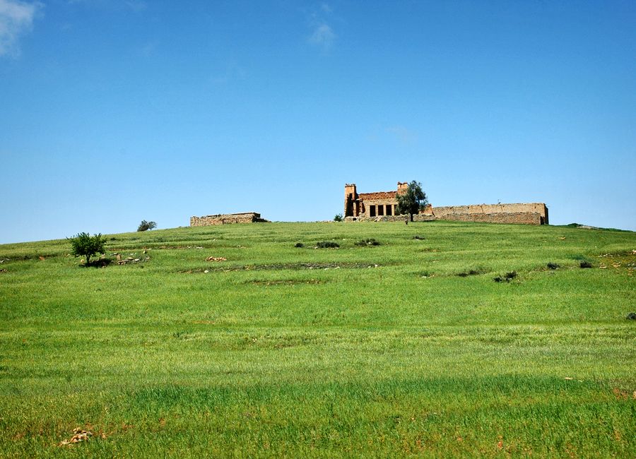 A picturesque view of historical ruins atop a green hill in Béni Mellal, Morocco.