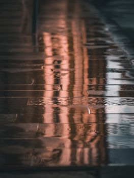 Rain soaked city street reflecting warm lights in a moody atmosphere.