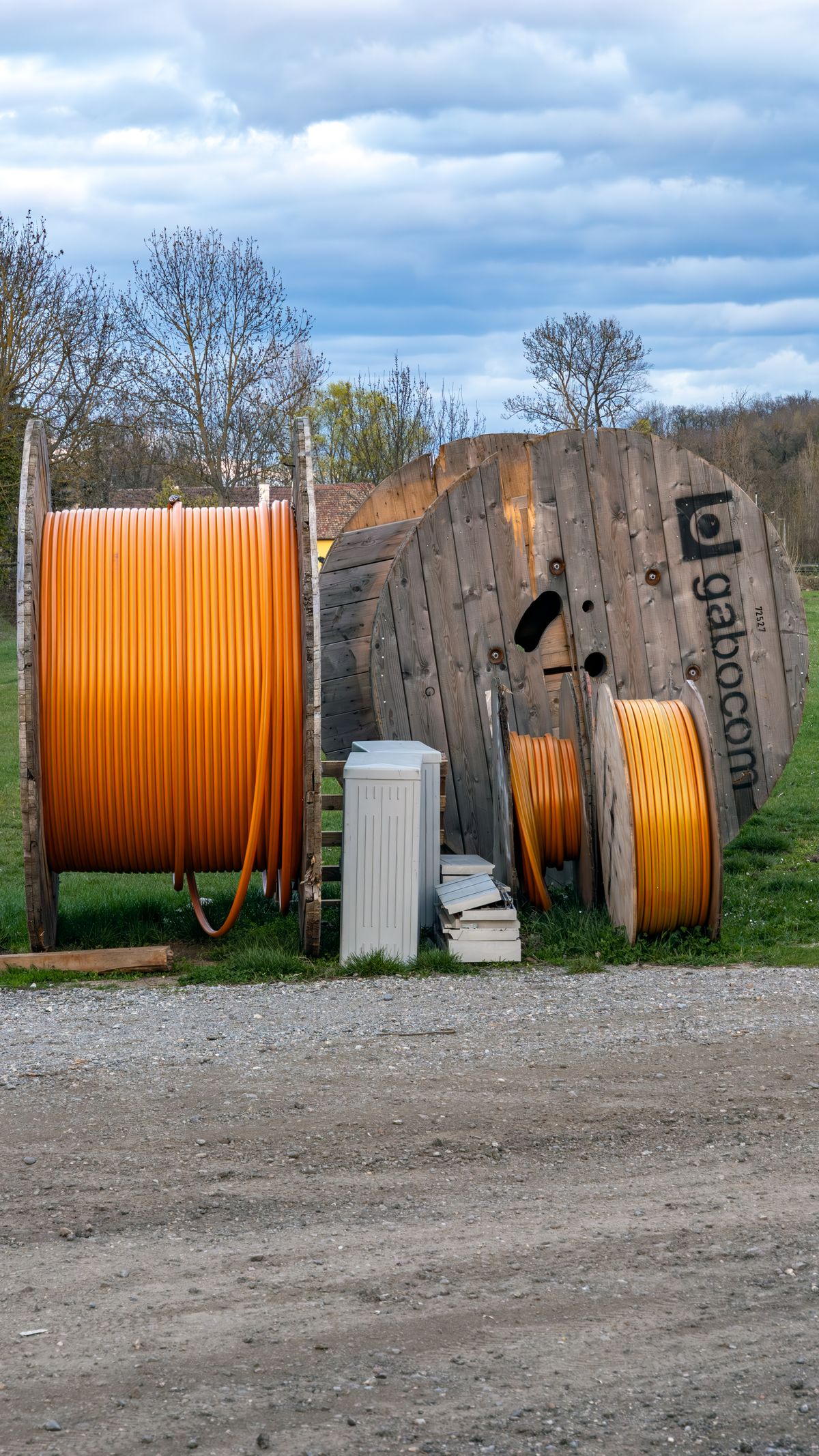 Wooden reels of orange power cable stored in an outdoor yard