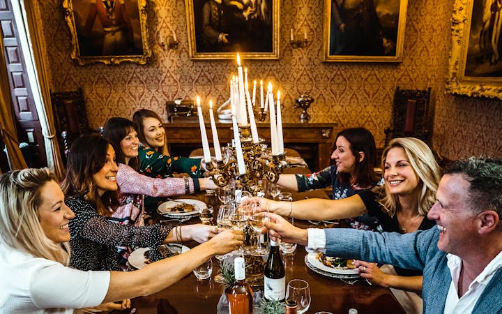 A group of friends sharing a joyful dinner party toast in an elegant London dining room.