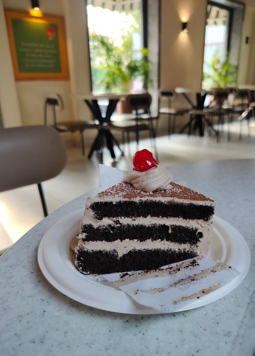 Free Close-up of a rich chocolate cake slice topped with cherry, captured indoors at a cafe. Stock Photo