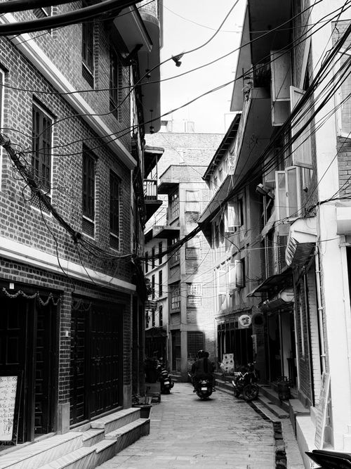 Free Explore the architectural charm of a narrow Kathmandu alleyway in this black and white photo, highlighting urban life. Stock Photo