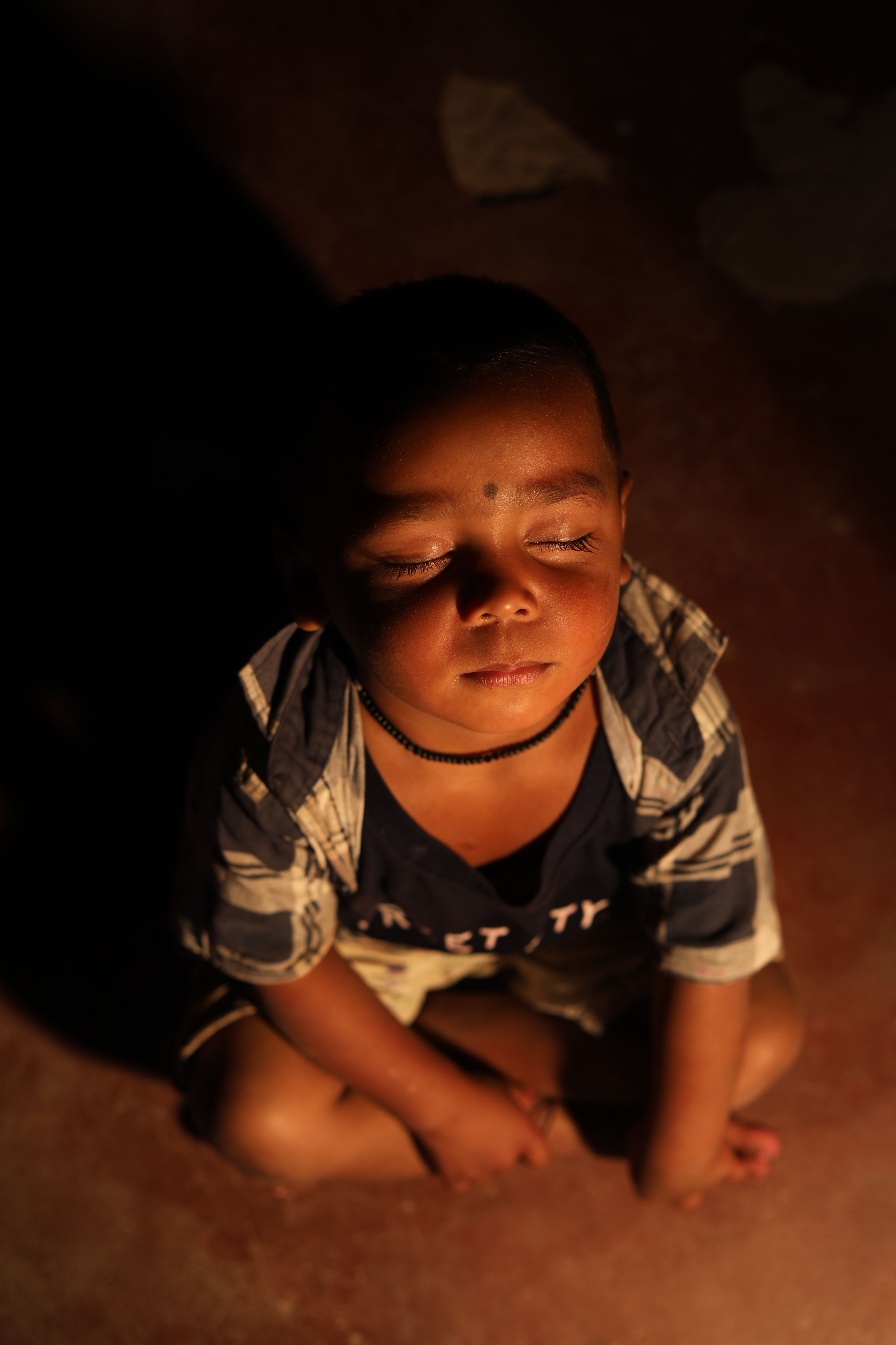 A serene portrait of a meditative child in Lalakapa, India, glowing in soft light.