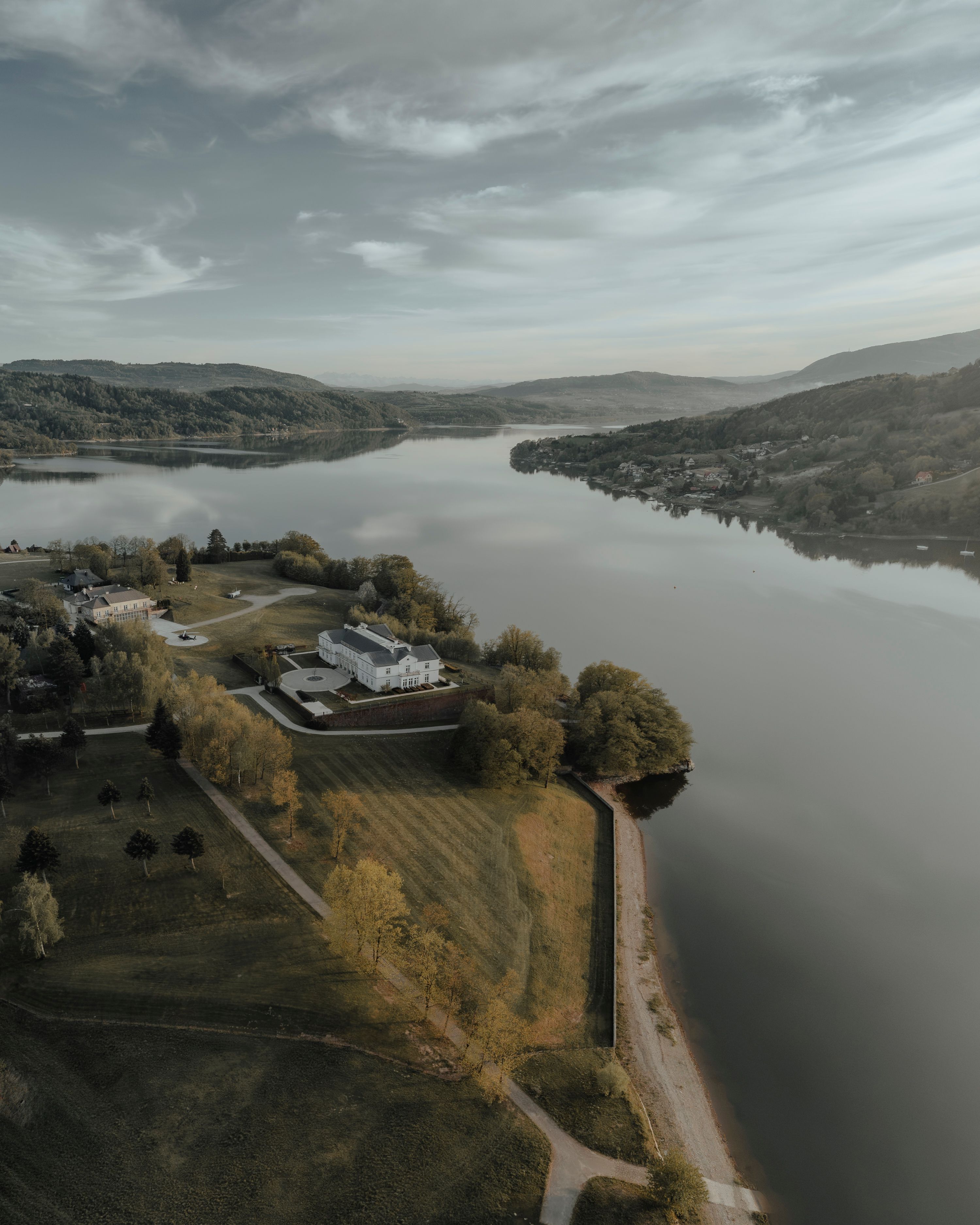 A tranquil aerial view of a lakeside area in Województwo małopolskie, Poland, embracing the serene twilight atmosphere.