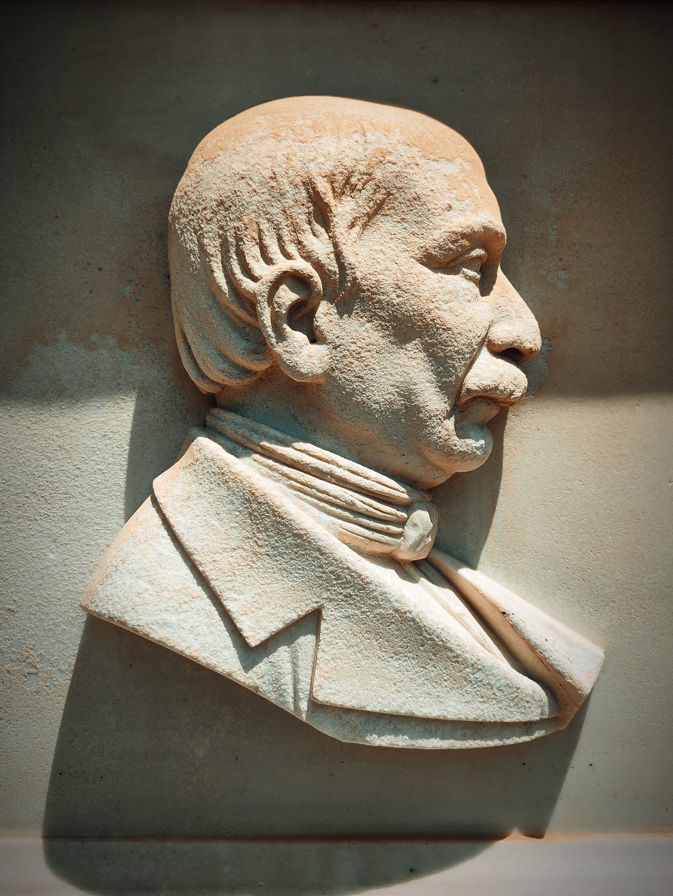 Side profile of an aged stone relief sculpture of a distinguished older gentleman.